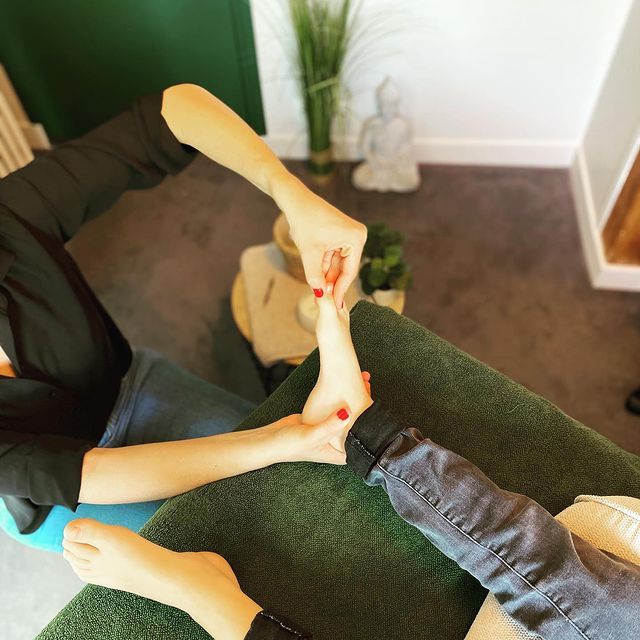 thérapeute effectuant une séance de réflexologie plantaire sur une personne allongée